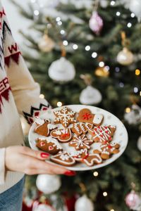 Kaboompics - Woman in a white Christmas sweater holds gingerbread cookies on plate