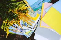 Kaboompics - Yellow flowers with postcards and colourful envelopes