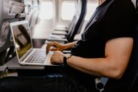Unrecognizable man with notebook sitting inside an airplane