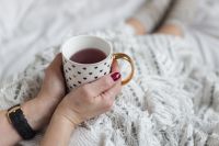 Soft photo of woman on the bed with the book and cup of tea in hands