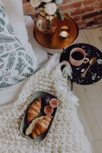 Croissants and figs on a green plate, a cup of coffee and a candle