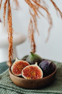 A wooden bowl containing fresh figs