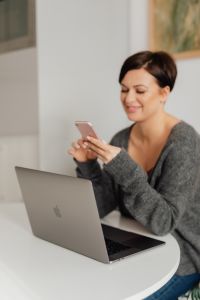 A brunette woman works with a laptop and a phone