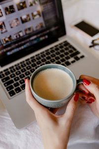 A woman works at a desk with a laptop and a cup of coffee