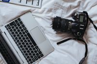 Kaboompics - Silver laptop and black camera on white bed sheets