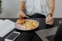 Kaboompics - Businesswoman eats at work hamburger and fries