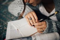 Kaboompics - Woman in a grey sweater taking notes in an organizer