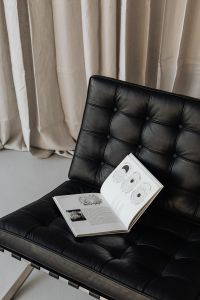Kaboompics - An open book lies on a black leather Barcelona chair