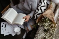 Kaboompics - A woman in a sweater reads a book