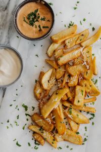 Variety of Fries with Creamy Sauce and Parsley Garnish