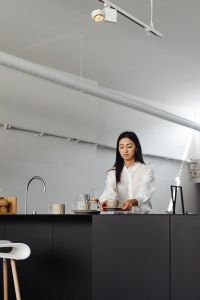 An adult young Asian woman pours coffee into a cup from a Chemex