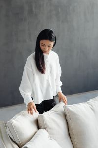 Young Asian woman improves cushions on linen couch