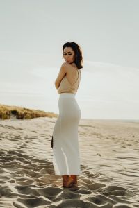 Young stylish woman poses on the beach at sunset