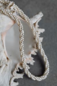 A large shell with a pearl necklace on it