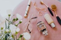 Makeup brushes, eyelash curler & a bottle of perfume on pink velvet