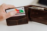 Kaboompics - Closeup man hand open brown genuine leather wallet with banknote and credit cards on marble background with clipping path