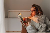 Kaboompics - A woman holds a burning candle in her hands - reading a book