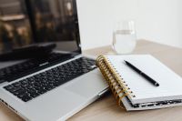 Laptop - compter - desk - glass of water - Macbook - AirPods - Earphones - Notebook - Pen