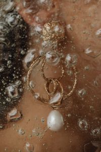 Details of gold jewelry - beautiful woman wearing a silk shirt