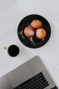 Marble desk with laptop, homemade Polish doughnuts and coffee