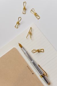 Fountain pen, clips and notebooks on a white desk