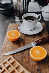 Cup of coffee, knife, waffle, oranges