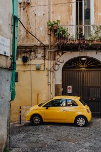 Yellow modern little car, Fiat 500, parked on a street in Naples