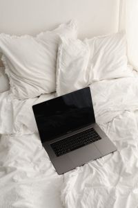 Kaboompics - Working with a laptop in bed - white cotton bedding