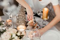 Kaboompics - A woman decorates a Christmas table with silver decorations and white porcelain tableware