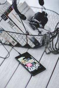 Kaboompics - Black smartphone and headphones and a basket of books