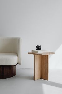 Modern oak side table - armchair with light boucle fabric - minimalist interior - book