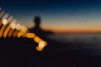 Light painting. The man waving fairy lights at the sea at sunset.