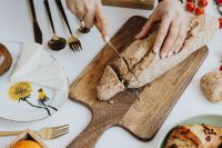 Kaboompics - Woman is cutting bread on cutting board