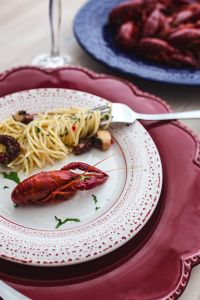 Kaboompics - Fancy dinner with seafood pasta, crayfish and red wine by the table decorated with roses