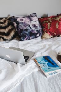 Bed full of pillows and notebooks with Apple gadgets