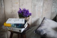 Kaboompics - Books and purple flowers on a wooden stool by the bed