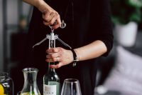Kaboompics - Hands opening wine bottle with corkscrew
