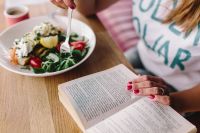 Woman eating breakfast and reading a book