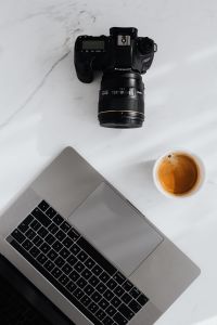 Coffee, laptop and camera on a white marble table