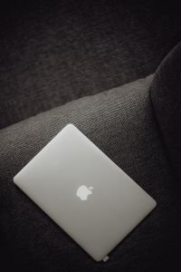 Close up view of closed laptop lying on grey armchair
