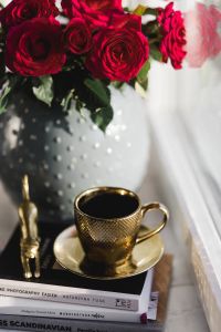Gold cup of coffee and red roses bouqet