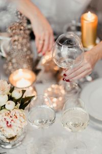 A woman decorates a Christmas table with silver decorations and white porcelain tableware