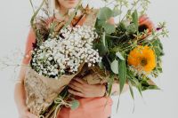 Kaboompics - A woman holds many different flowers and leaves in her arms
