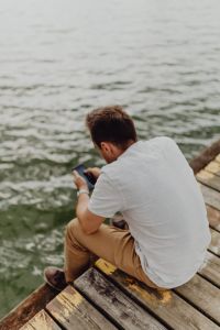 Kaboompics - The man is using his phone at the lake