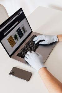 Hands in hygienic glove typing on laptop