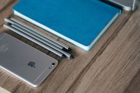 Kaboompics - Silver iPhone with a blue notebook and pencils