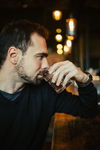 Handsome young man having a whiskey in a pub