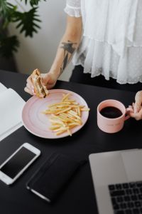 Kaboompics - Businesswoman eats at work hamburger and fries, drink coffee