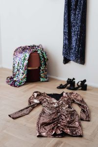 Kaboompics - colored sequin dresses and boots lie on a wooden parquet, blue dress hang on the white wall