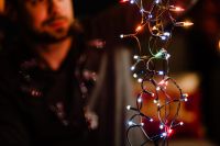 Kaboompics - A handsome young man with Christmas tree lamps